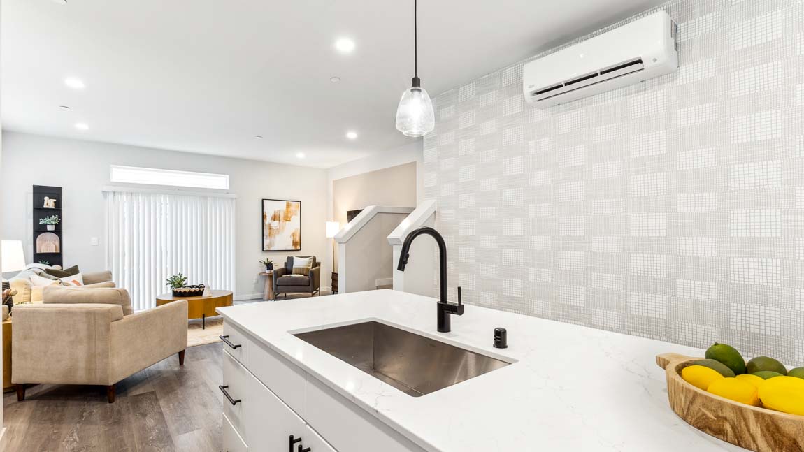 Kitchen connected to living area and stairway access to lower ﬂoor and stairway access to upper ﬂoor