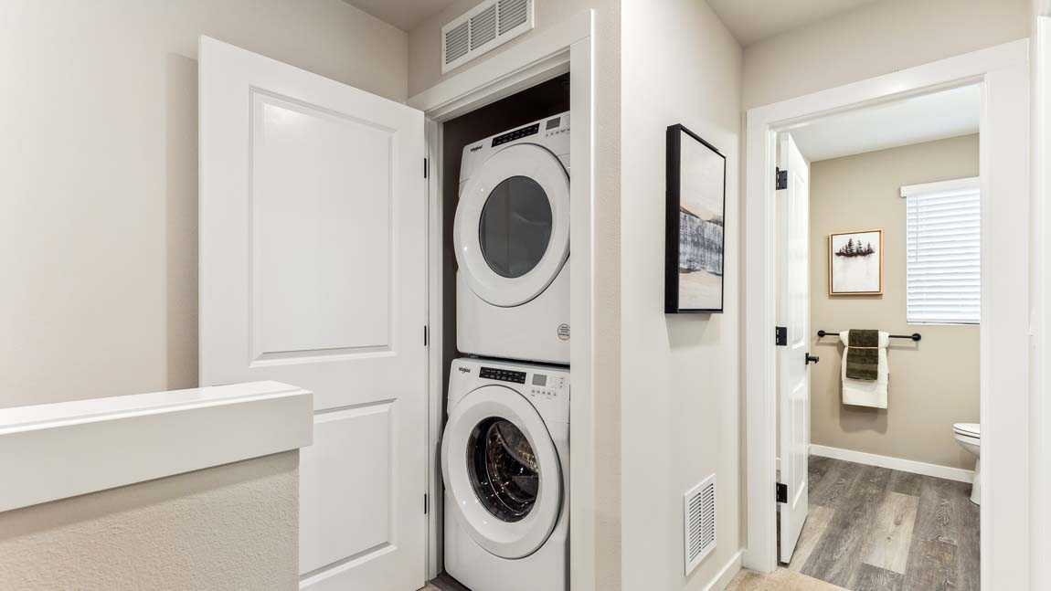 Stacked washer and dryer in laundry closet on upper ﬂoor near stairwell