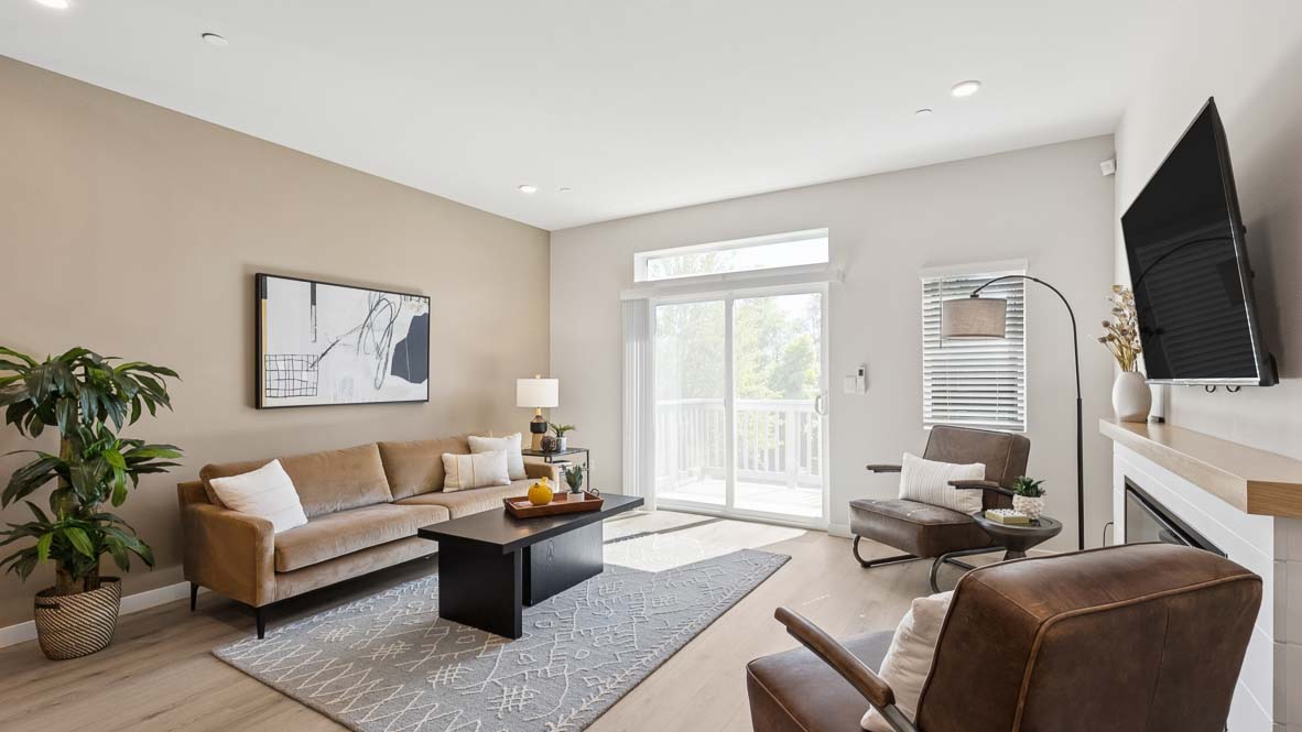 Bennett model living room with bright windows and slider door access to balcony