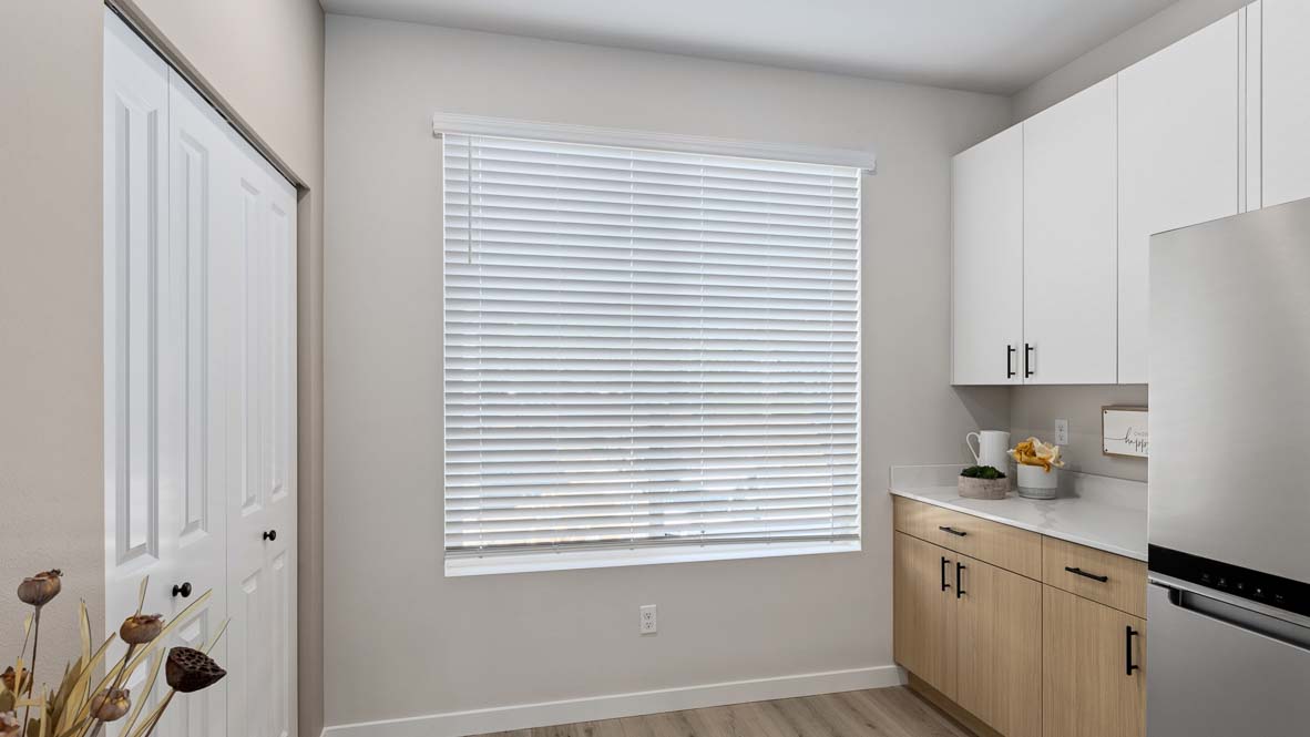 Closer view of large kitchen window and stainless-steel refrigerator inside the Bennett model home at Cathcart Crossing