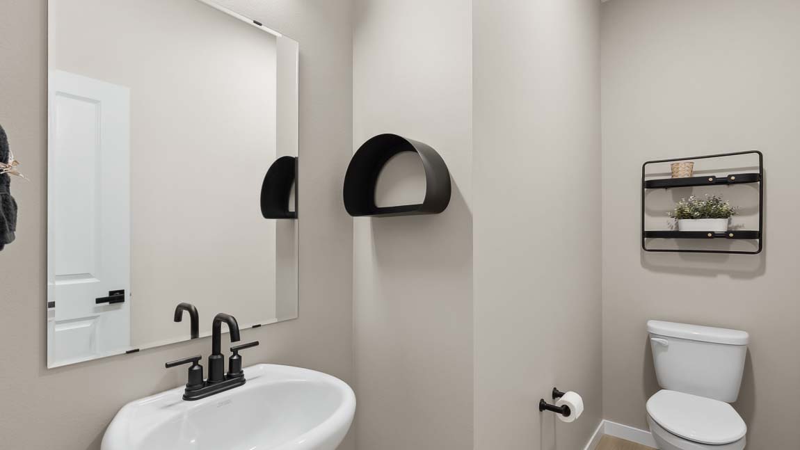 Main floor powder room with pedestal sink nearby kitchen