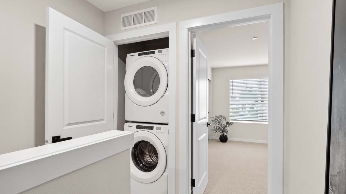 Laundry room closet near stairwell with stacked washer and dryer