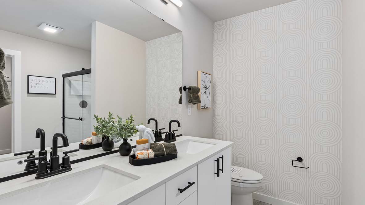 Private en-suite primary bathroom featuring double sink vanity and white modern cabinetry