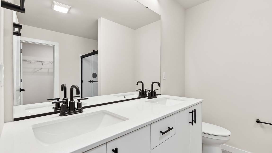 Primary bath double sinks and walk-in shower with walk-in closet