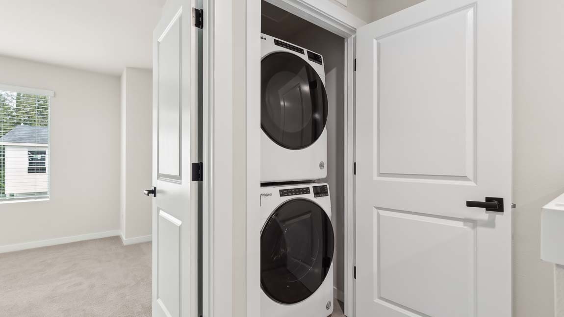 Stacked washer and dryer in laundry room near Bedroom 2 Bath 2 and stairway access to main floor