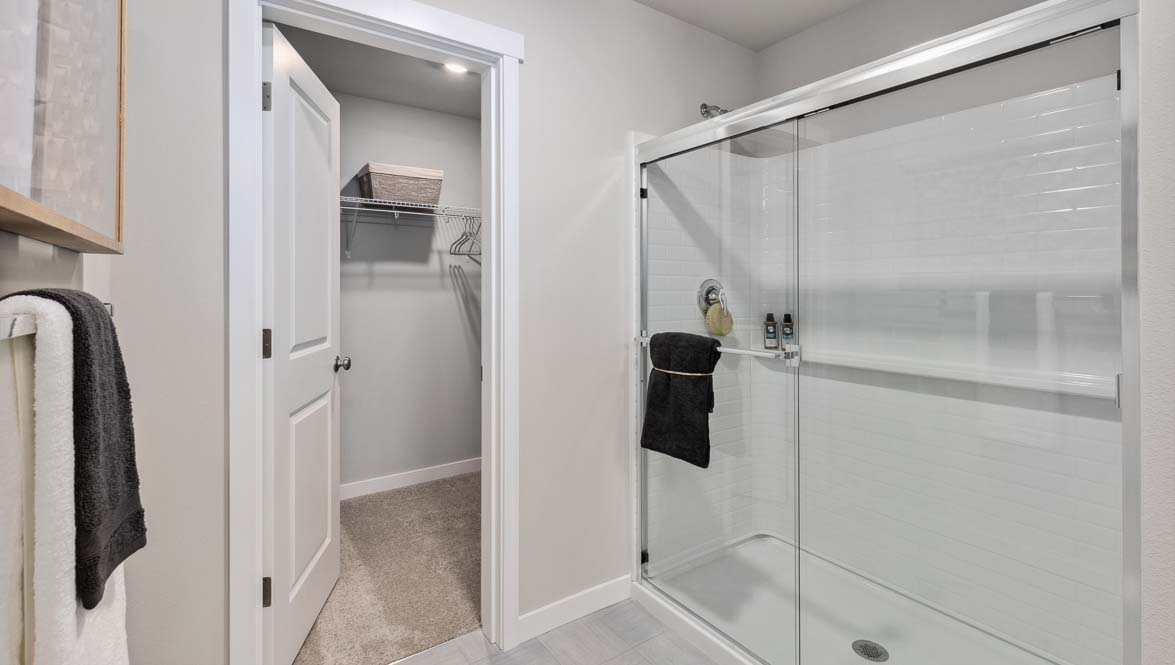 Modern bathroom featuring a glass-enclosed shower, spacious walk-in closet, tile flooring, and neutral finishes.