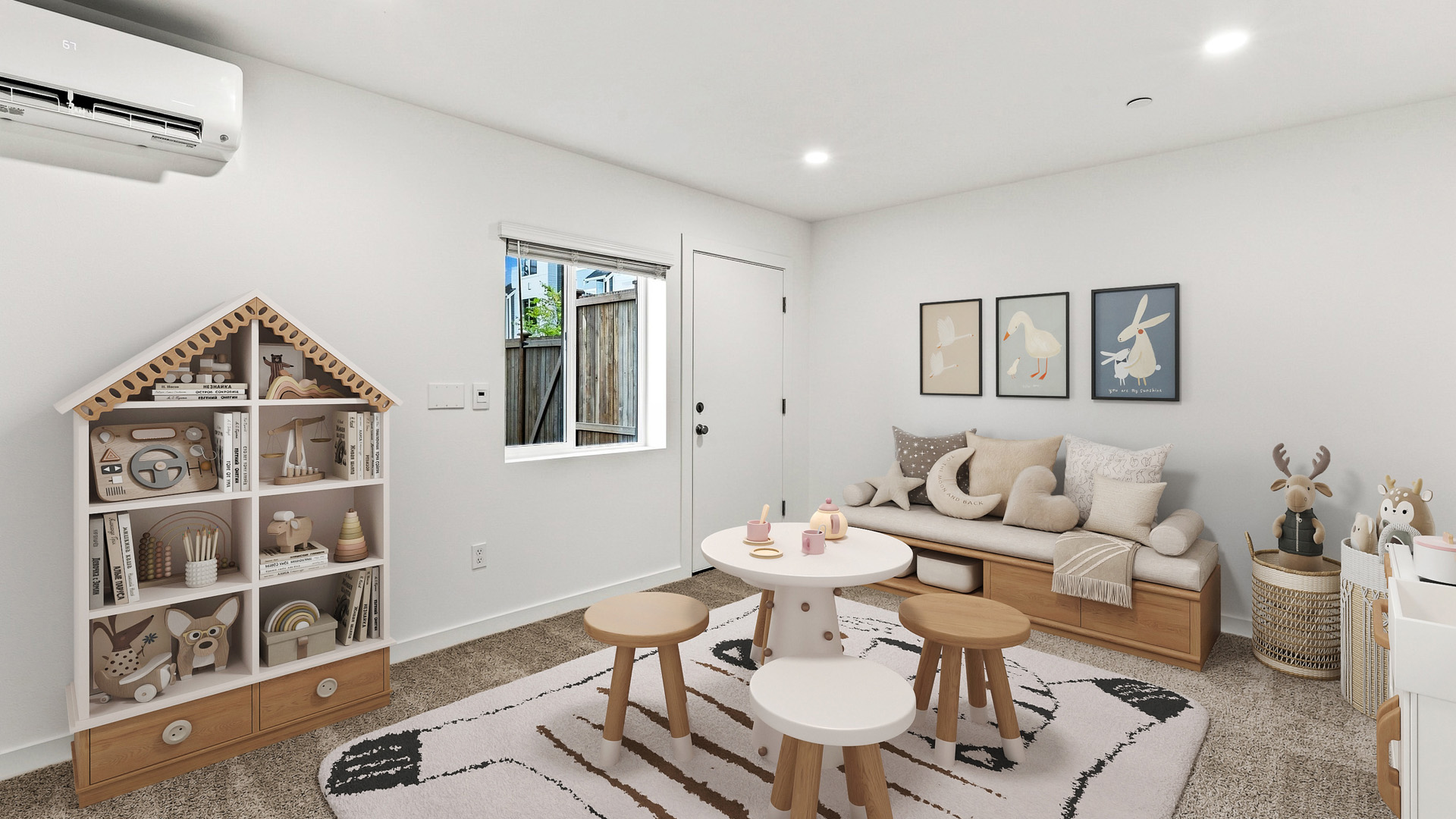 Versatile flex room staged as a children's playroom with toy house bookshelf, activity table, sofa seating, and decorative wall art.