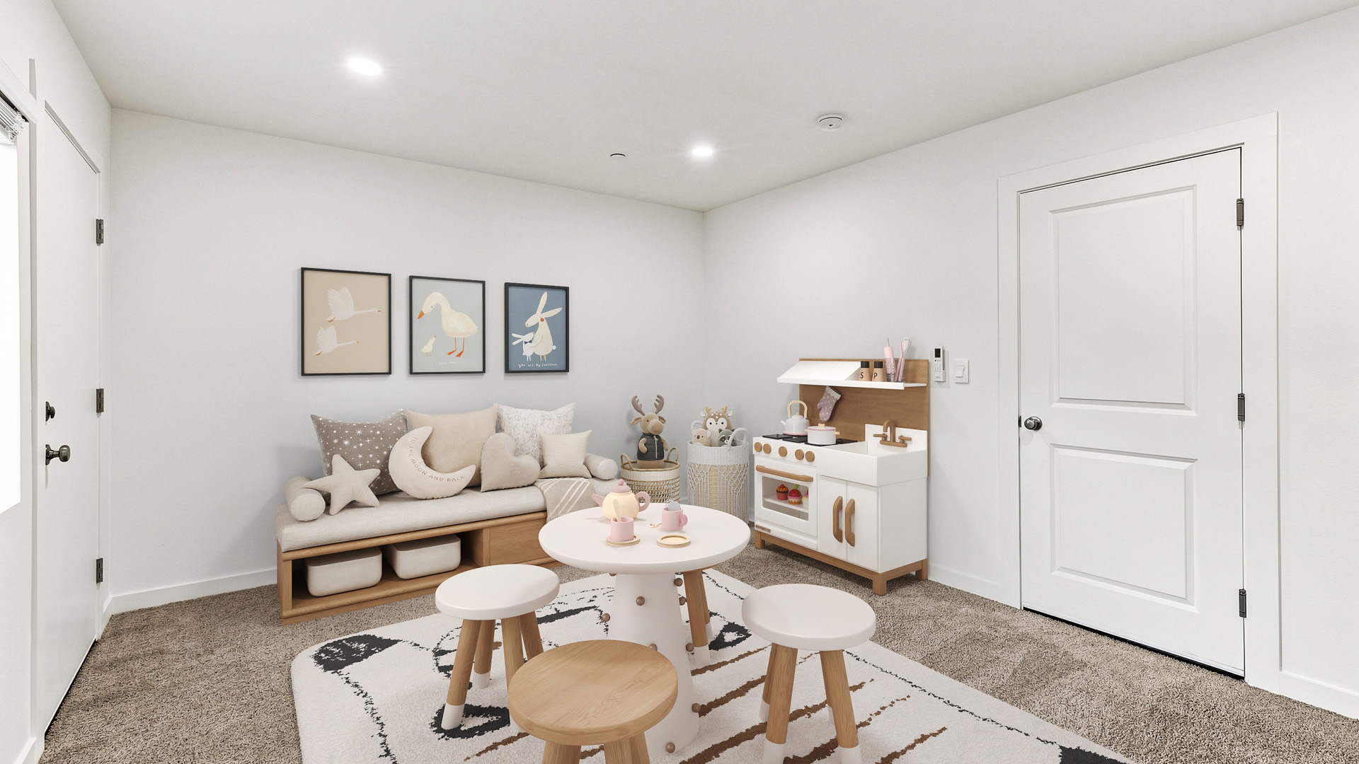Children's playroom featuring a toy kitchen, small round table with stools, plush seating, storage baskets, and framed artwork.