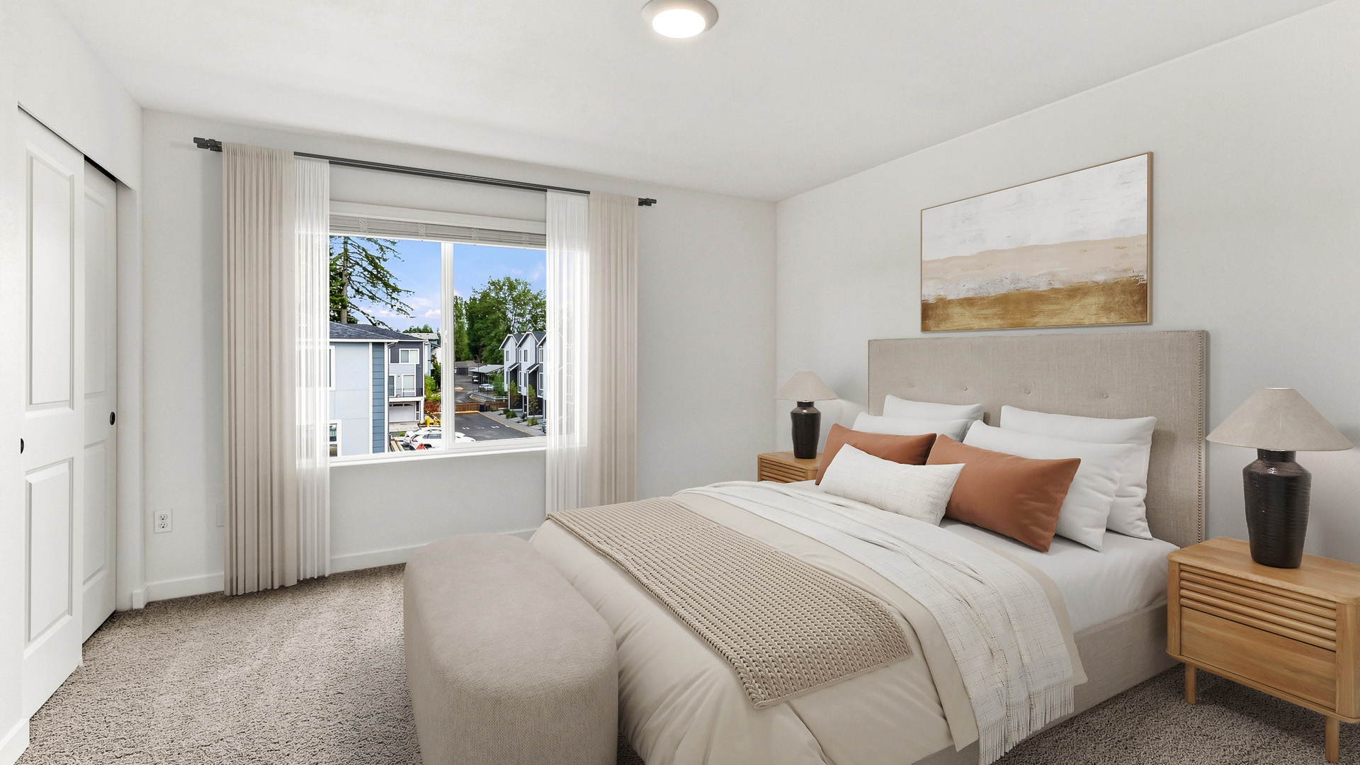 Bright primary bedroom with large window, upholstered bed, matching nightstands, decorative artwork, and neighborhood views.