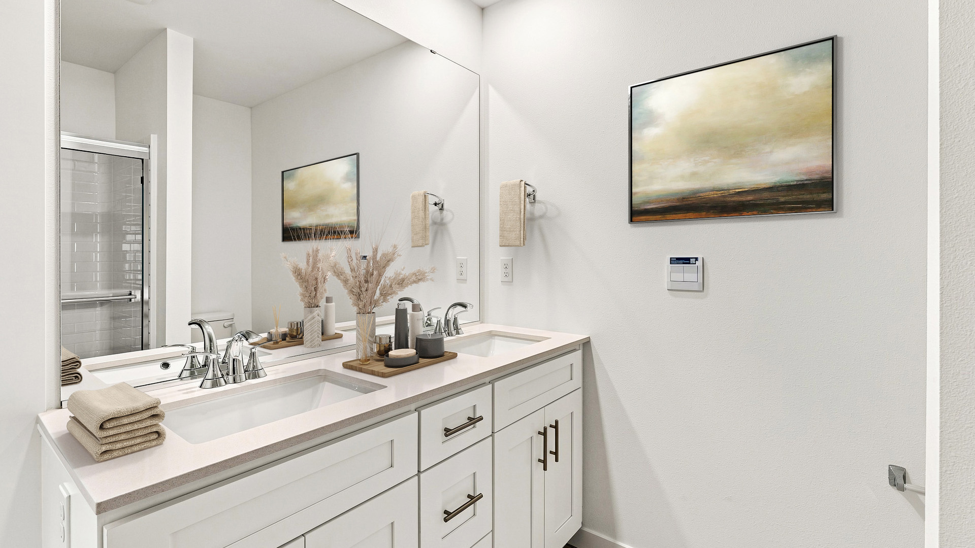 Modern bathroom with double-sink vanity, large wall mirror, white cabinetry, and decorative accents in neutral tones.