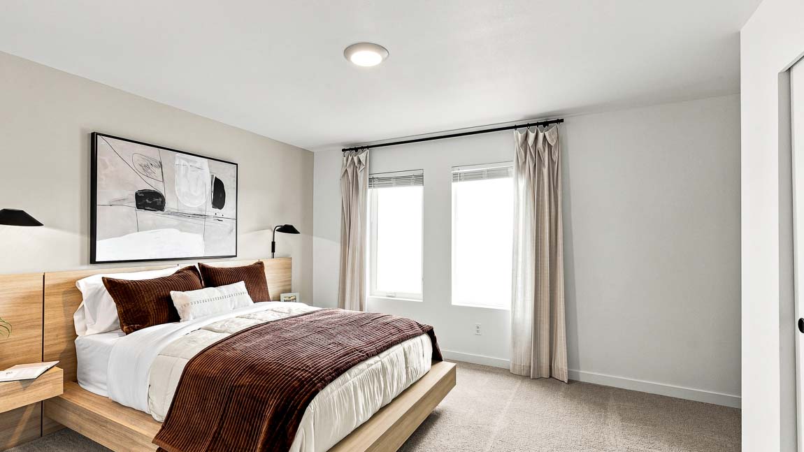 Spacious primary bedroom featuring large windows, plush carpeting, sliding closet doors, and built-in shelving.