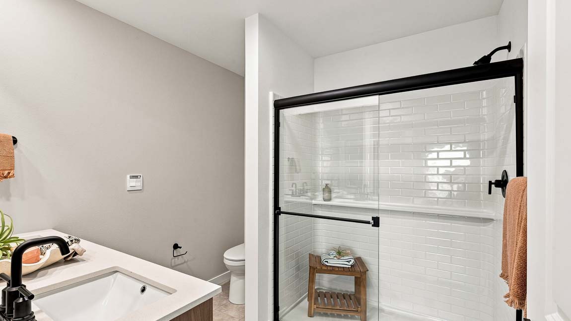 Primary bathroom vanity with dual sinks, large mirror, wood cabinetry, and modern black hardware.