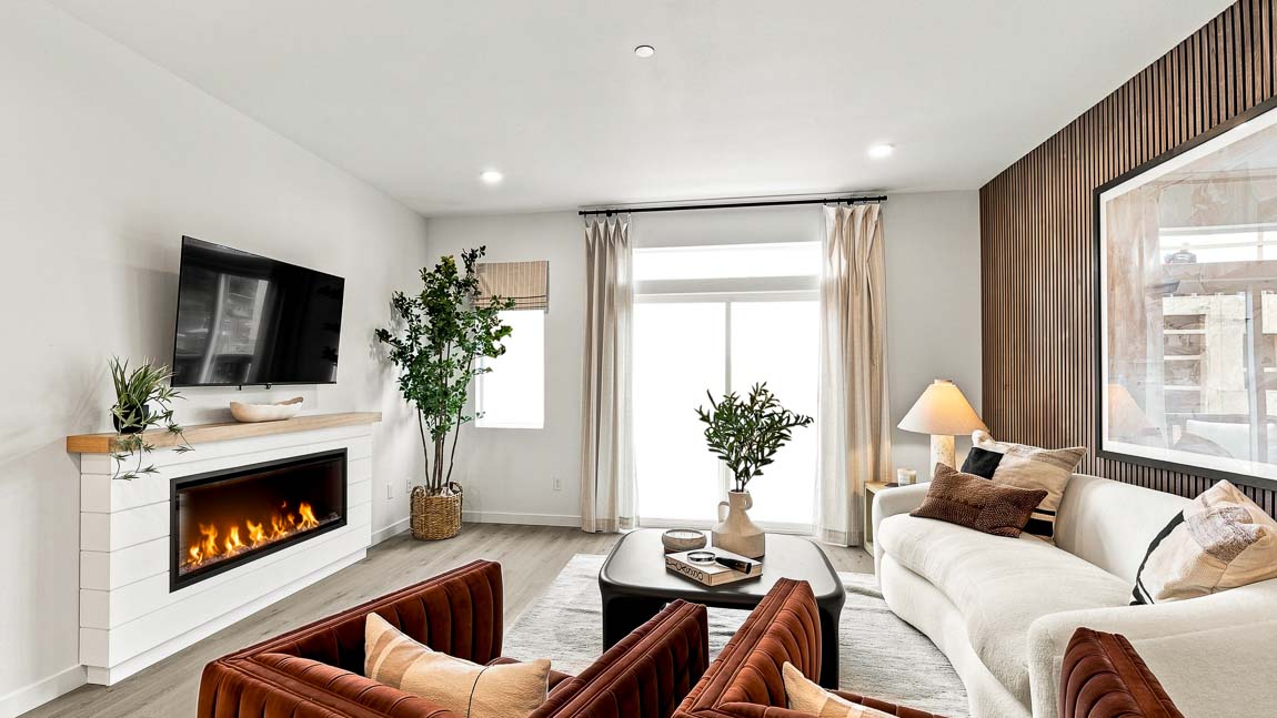 Bright contemporary living room featuring a linear fireplace, wall-mounted TV, white sofa, and wood slat accent wall.