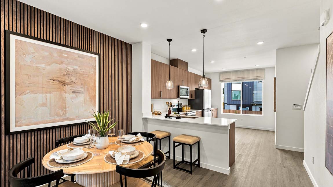 Open dining room and kitchen featuring a quartz peninsula, pendant lights, wood cabinetry, and modern finishes.