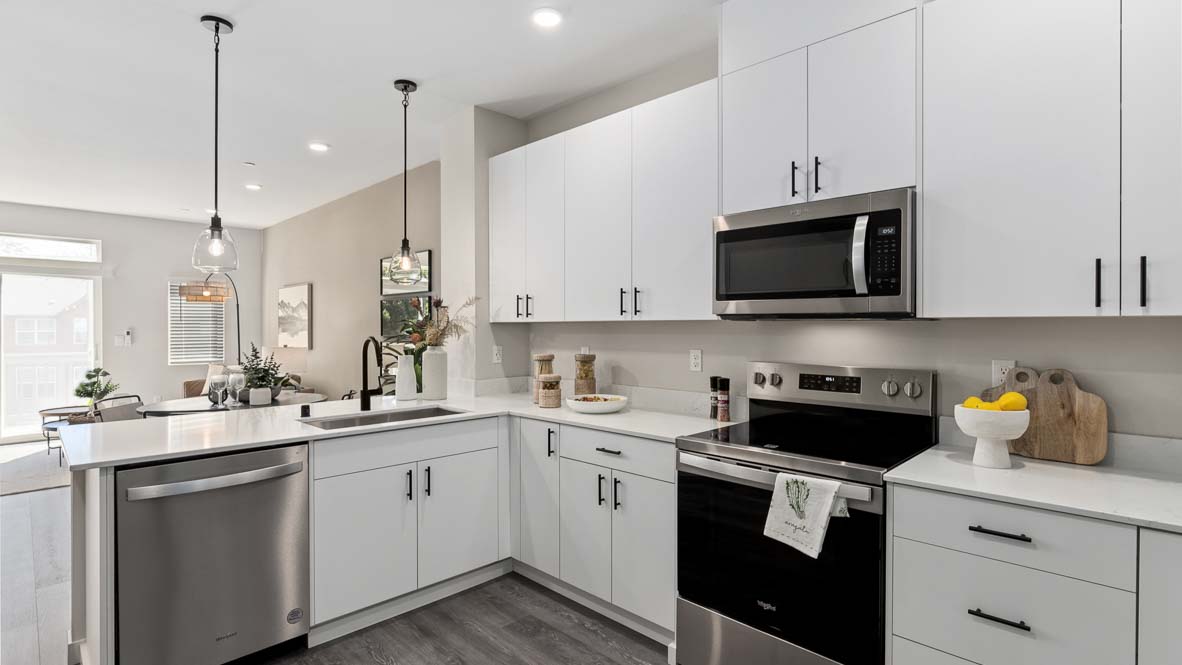 Contemporary kitchen featuring a large island, stainless steel dishwasher, electric range, microwave, and abundant cabinet storage.