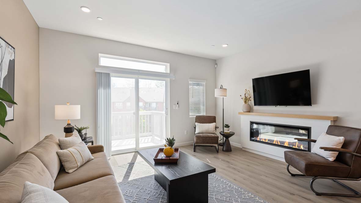 Contemporary living room featuring a sleek linear fireplace, wall-mounted TV, large sliding glass door, luxury vinyl plank flooring, and comfortable seating in a bright open-concept space.