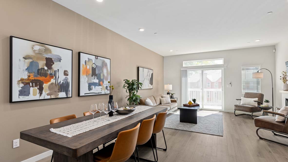 Open-concept dining and living area featuring a modern dining table, contemporary furnishings, large windows, luxury vinyl plank flooring, and abundant natural light throughout the space.