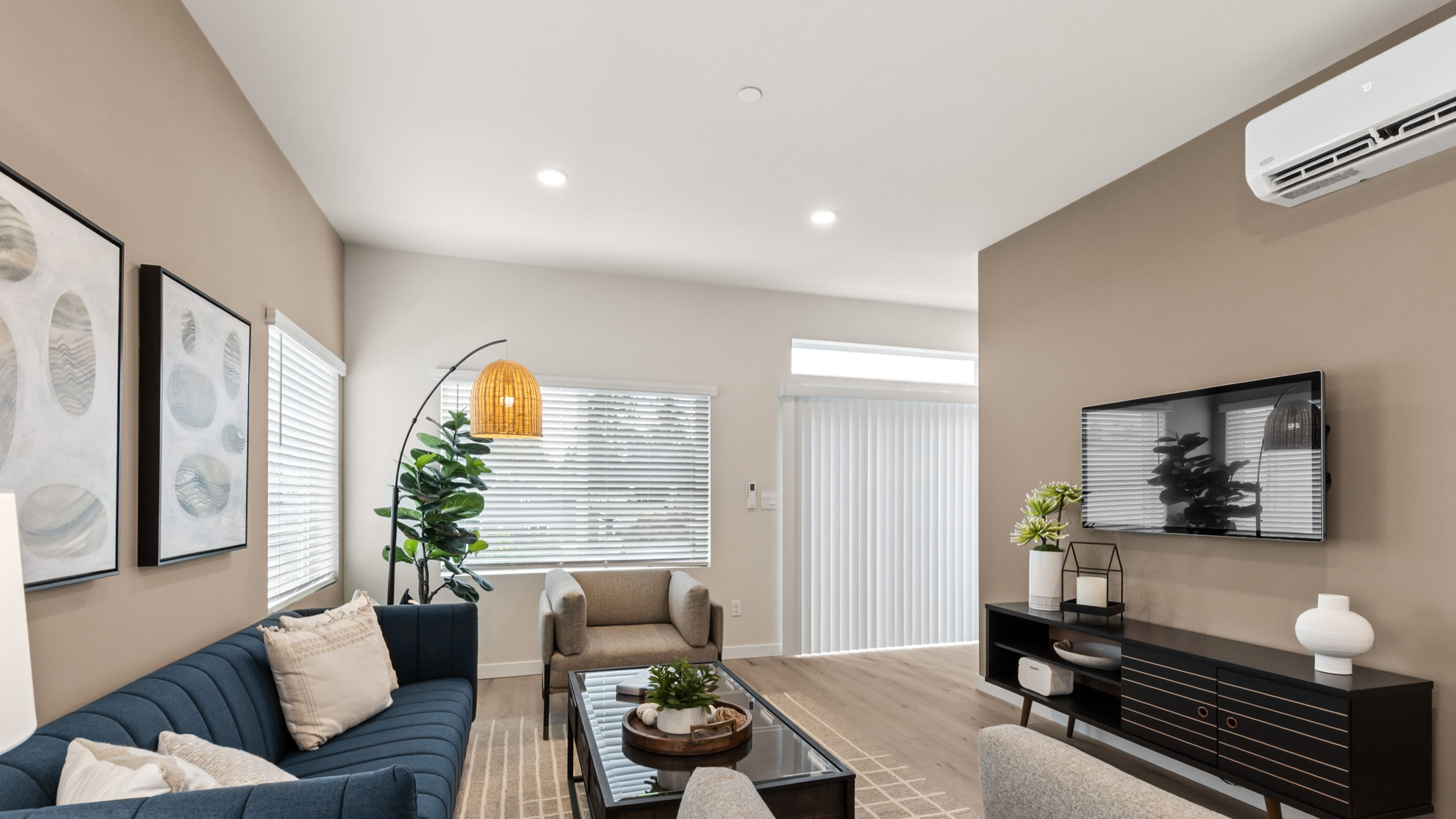 Contemporary living area with wall-mounted television, media console, accent lighting, and comfortable seating.