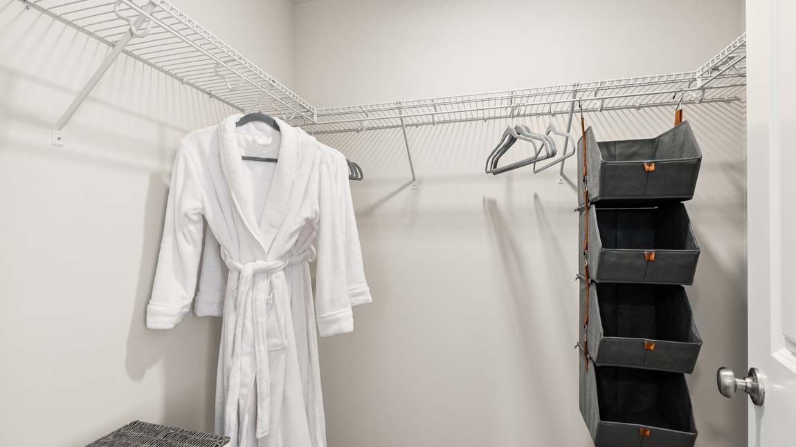 Walk-in closet with wire shelving, hanging rod, storage organizer, and ample wardrobe space.