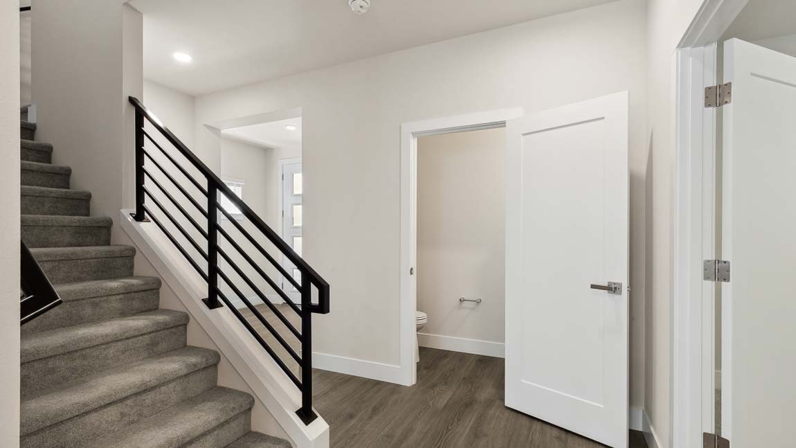 Staircase with sleek modern railing and main floor powder room