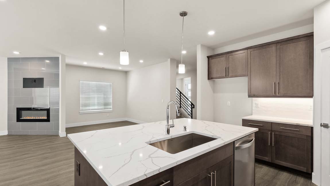 View from kitchen into dining and living space featuring cozy electric fireplace