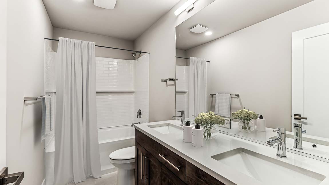Upper-level hallway bath featuring 2 sink vanity and shower tub combo