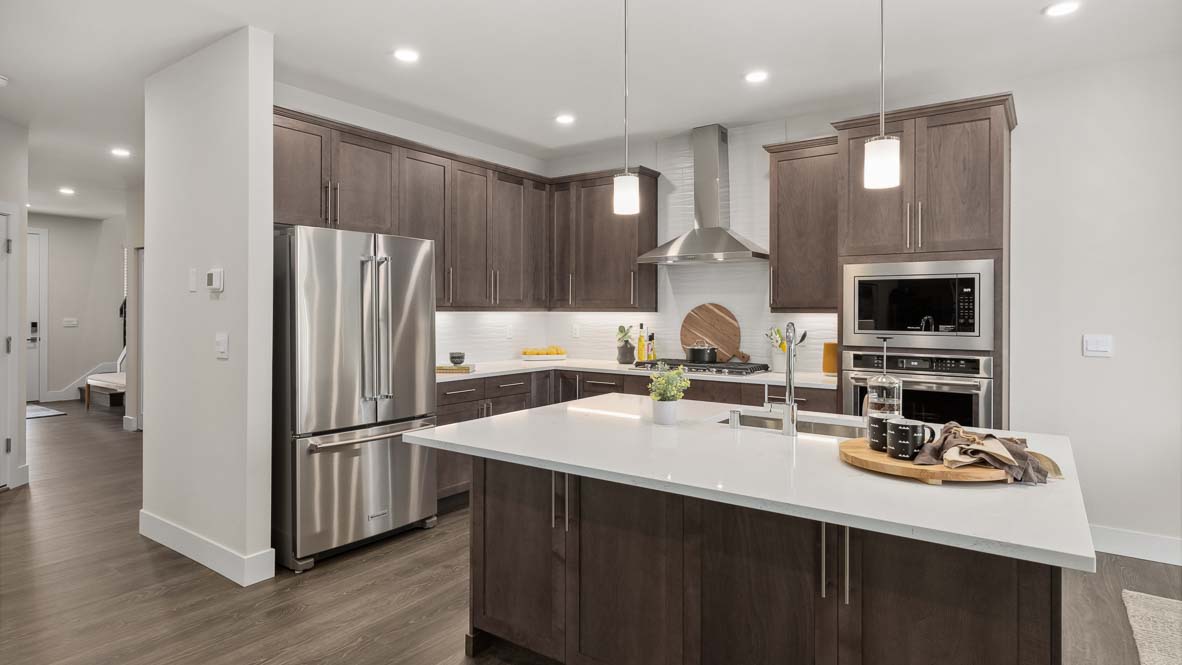Alternate view showing how entry foyer leads to kitchen with stainless steel appliances and LED under-cabinet lighting