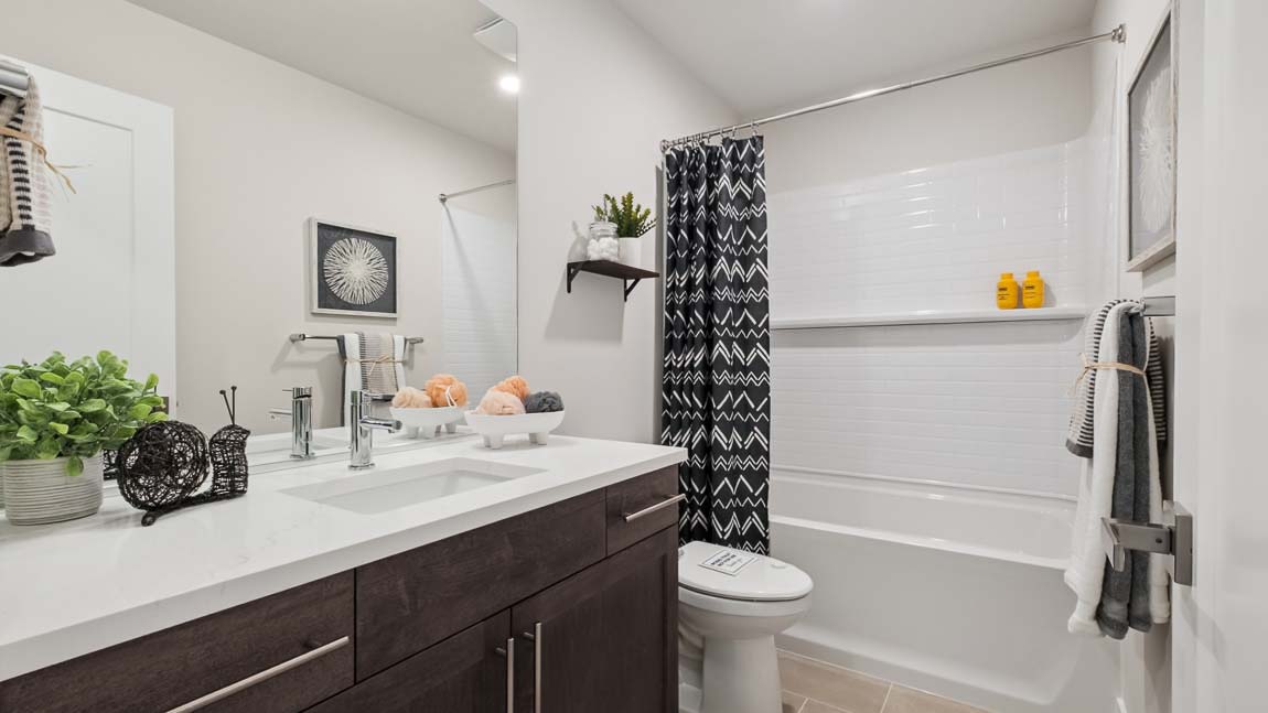 Upper floor secondary bathroom with shower tub combo chrome fixtures large mirror and tile backsplash