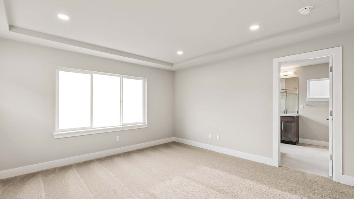 View of primary bedroom with peak into Primary bathroom