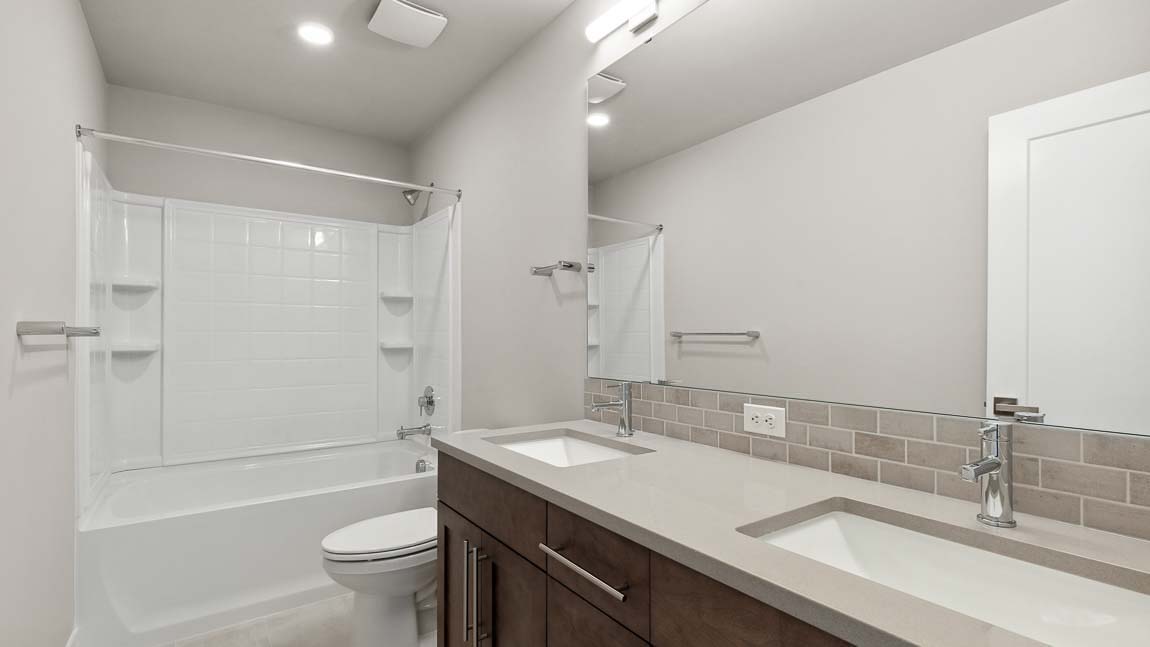 Upper-level hallway bathroom with shower and tub combo and 2 sink vanity