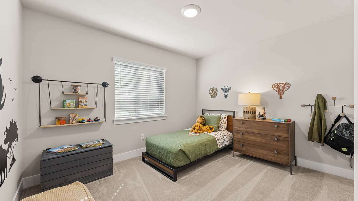 Secondary bedroom on upper floor with plush carpeting between third bedroom and primary bedroom