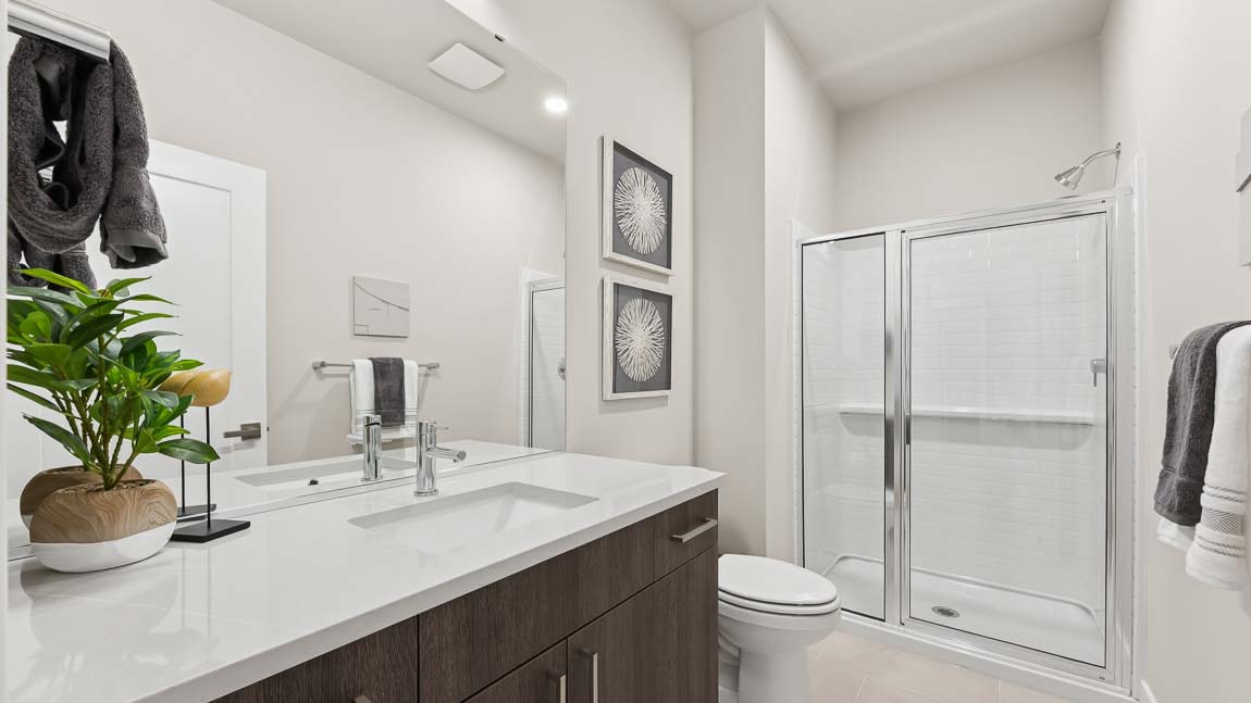 Main floor bathroom with shower and chrome fixtures and tile backsplash