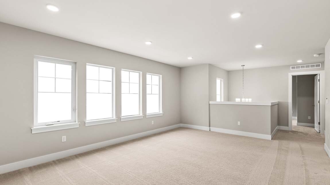 Expansive upper-level bonus room with plush carpeting, multiple windows, and an open loft-style layout.