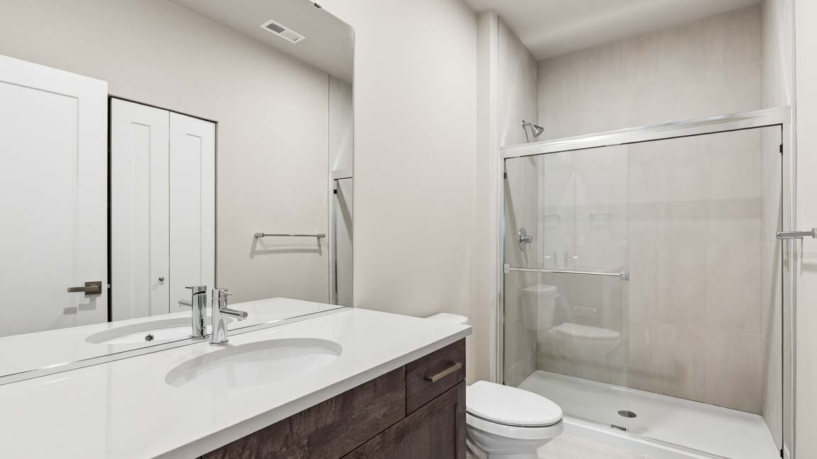 Modern bathroom with a single-sink vanity, quartz countertop, large mirror, and glass-enclosed walk-in shower.