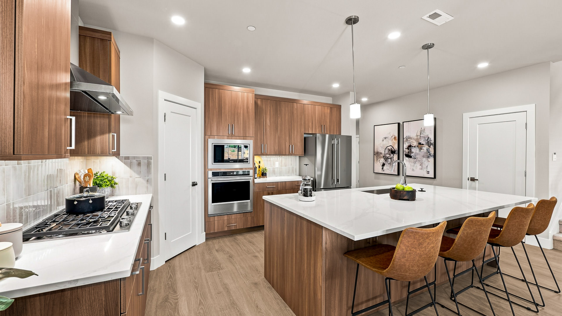 Spacious kitchen with quartz island, bar seating, built-in oven and microwave, and warm wood finishes.