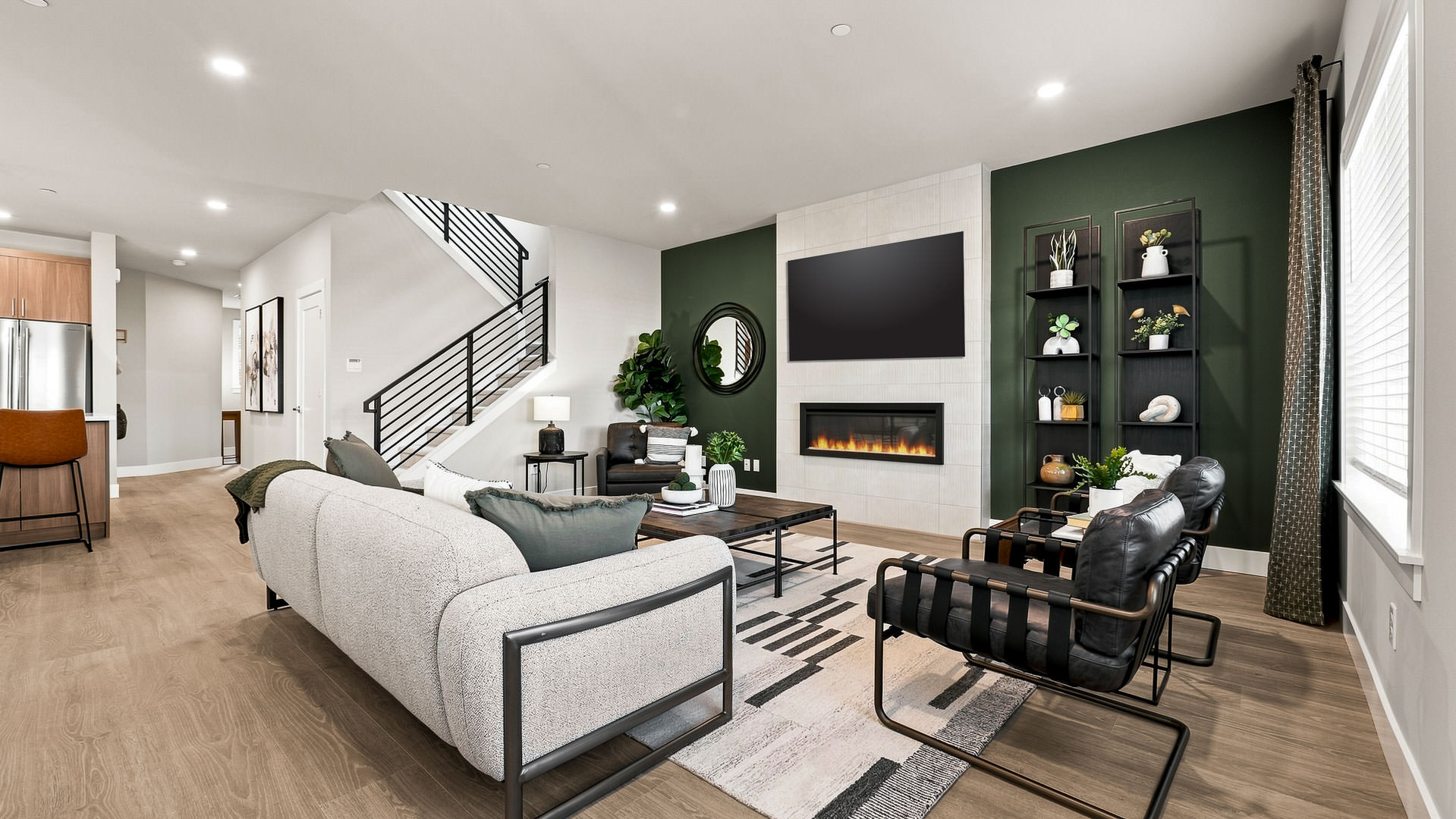 Open living area with fireplace feature wall, modern seating, staircase, and patterned area rug.