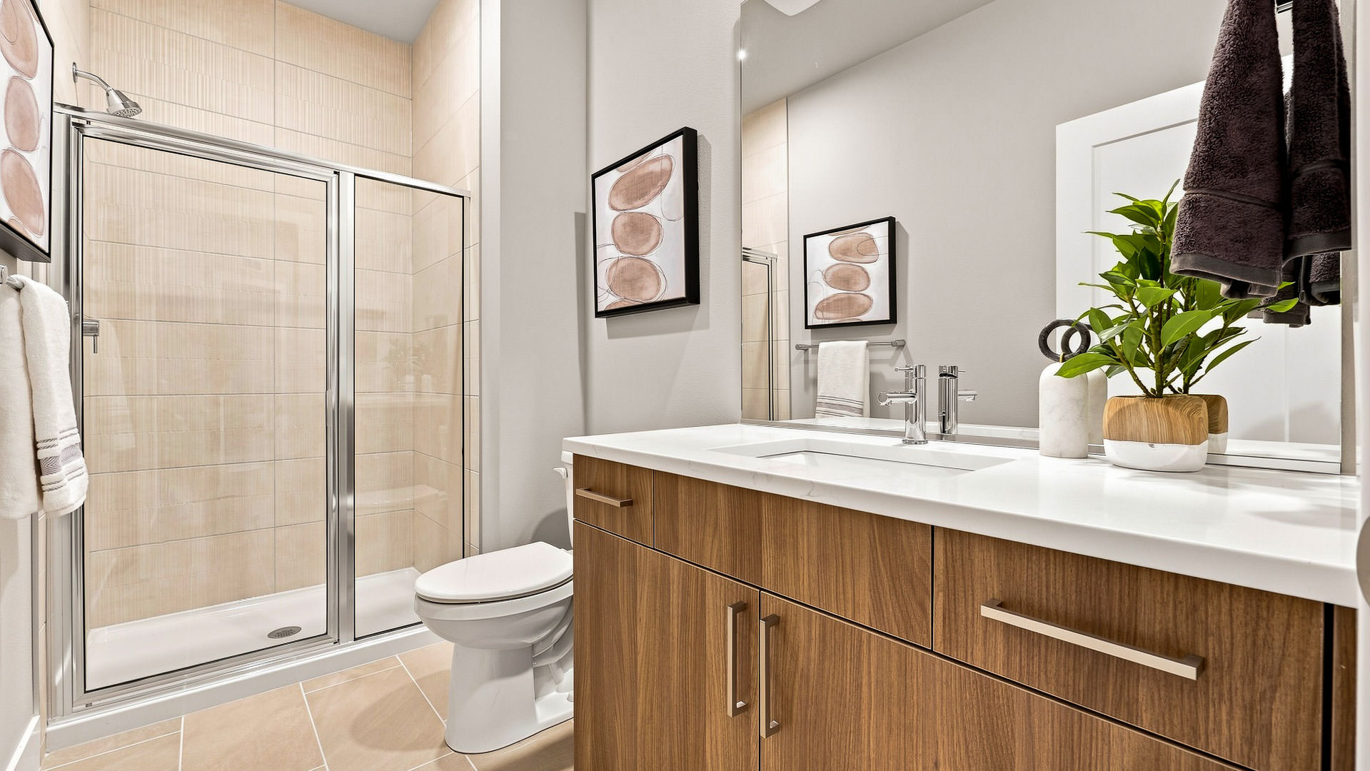 Bathroom with single vanity, framed mirror, toilet, and glass-enclosed shower with tiled walls.
