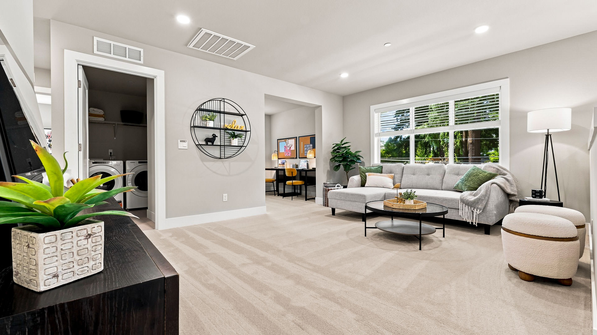 Bonus room with sectional sofa, round coffee table, large window, and nearby laundry closet.