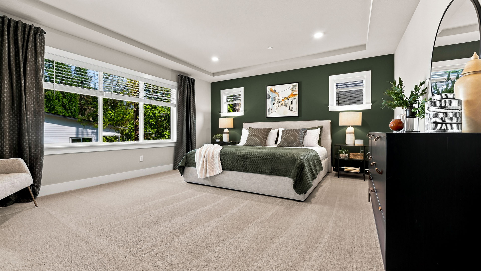 Primary bedroom featuring a large bed, green accent wall, bedside lamps, and expansive windows.