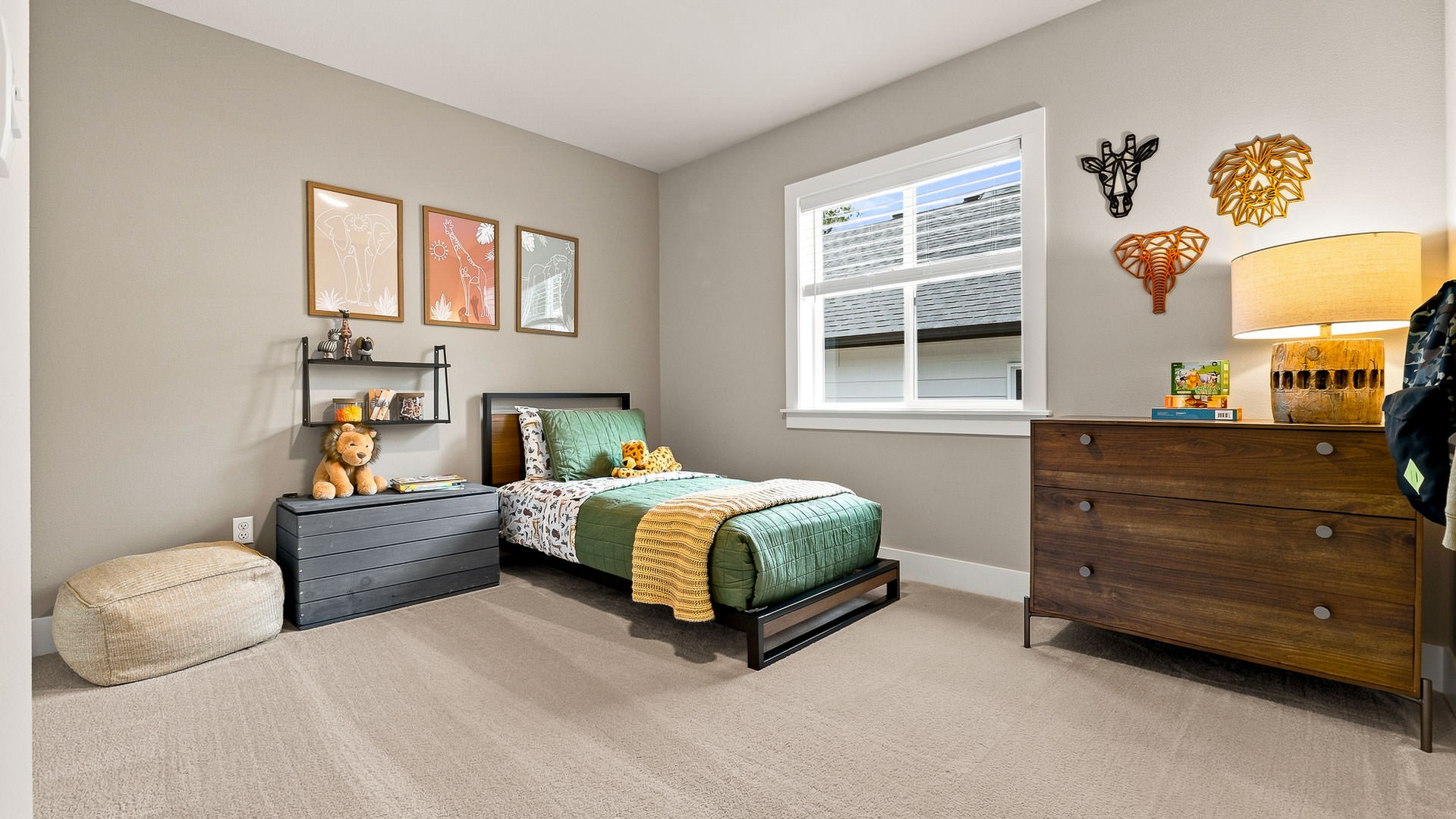 Children’s bedroom with twin bed, animal-themed wall art, dresser, and bedside storage.