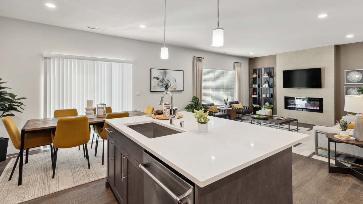 Open-concept kitchen, dining, and living area with large island, fireplace, and contemporary furnishings.