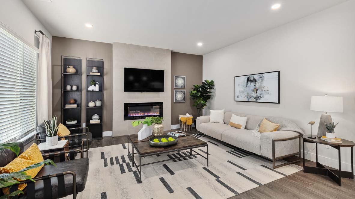 Contemporary living room featuring fireplace, mounted television, decorative shelving, and neutral furnishings.