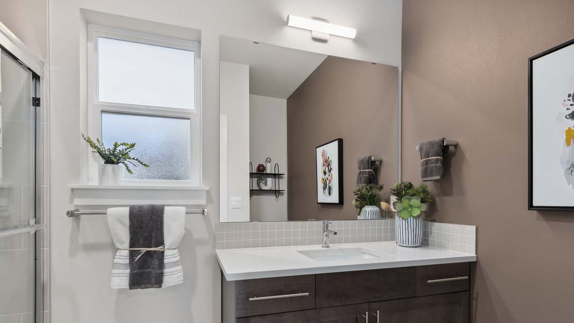 Bathroom with single vanity, large mirror, quartz countertop, and glass-enclosed shower.