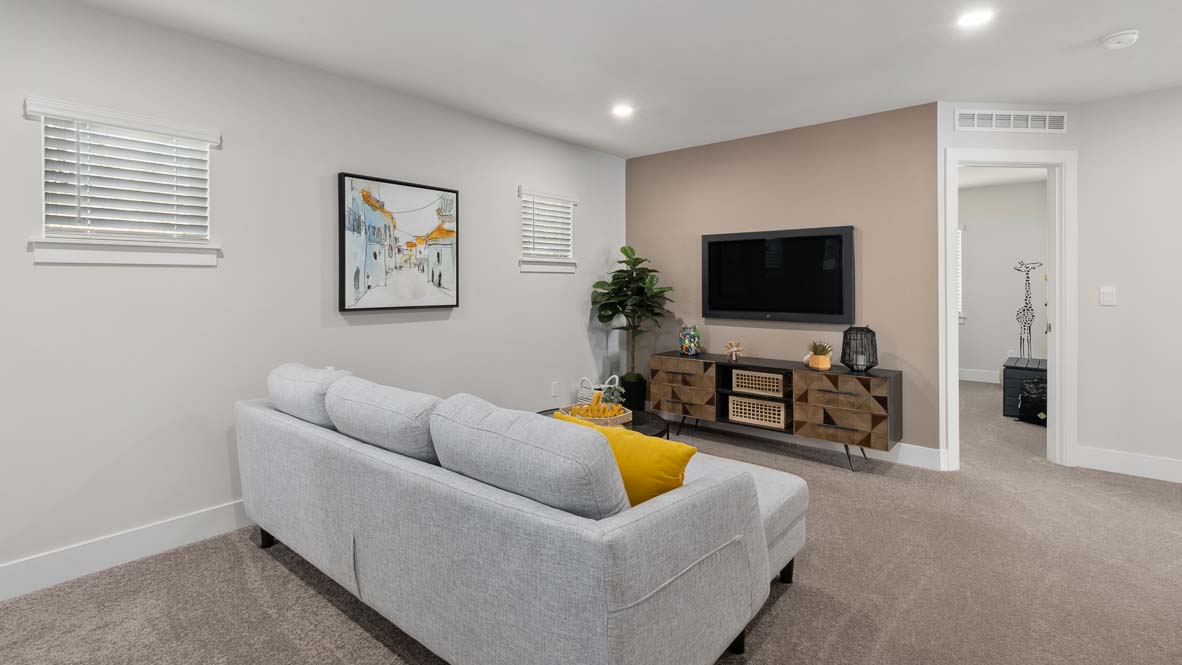 Bonus room with sectional sofa, wall-mounted television, media console, and soft carpet flooring.