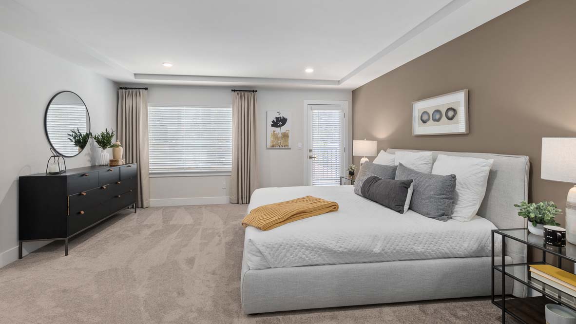 Primary bedroom featuring upholstered bed, large window, neutral décor, and spacious layout.