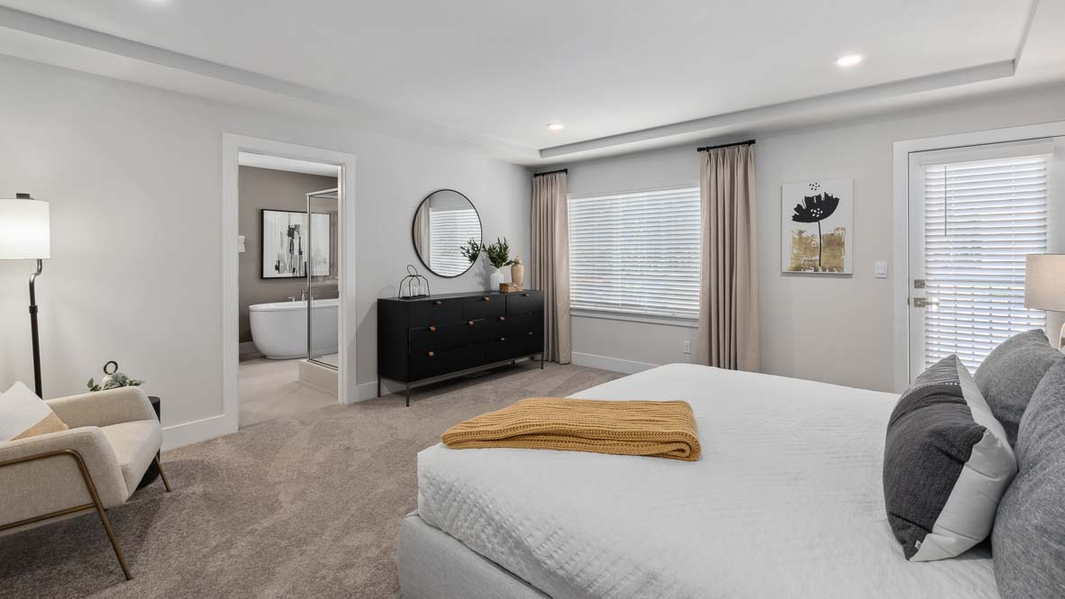 Expansive primary bedroom with tray ceiling, sitting area, and private bathroom access.