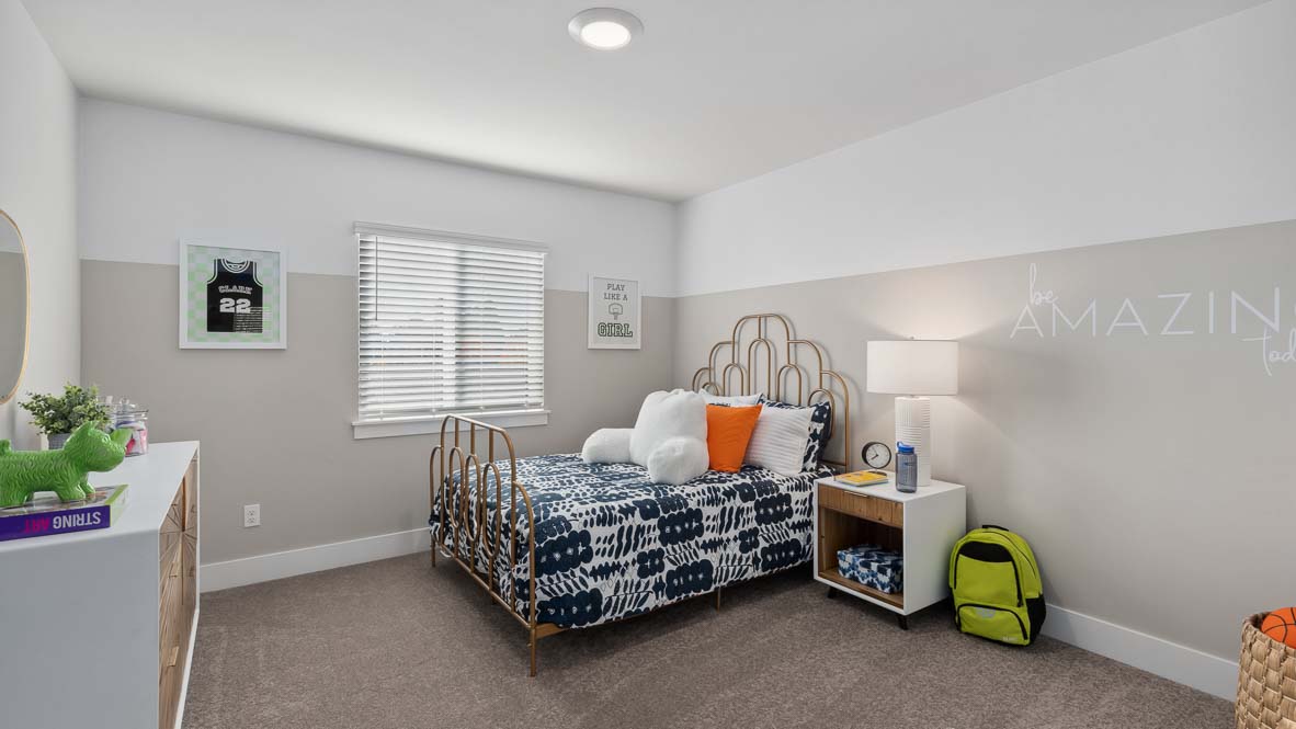 Secondary bedroom with decorative metal bed frame, patterned bedding, and bright window.