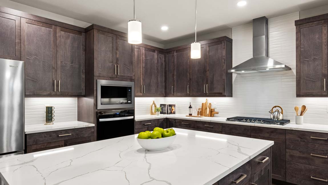 Modern kitchen featuring oversized center island, stainless steel refrigerator, dishwasher, and extensive cabinet storage.