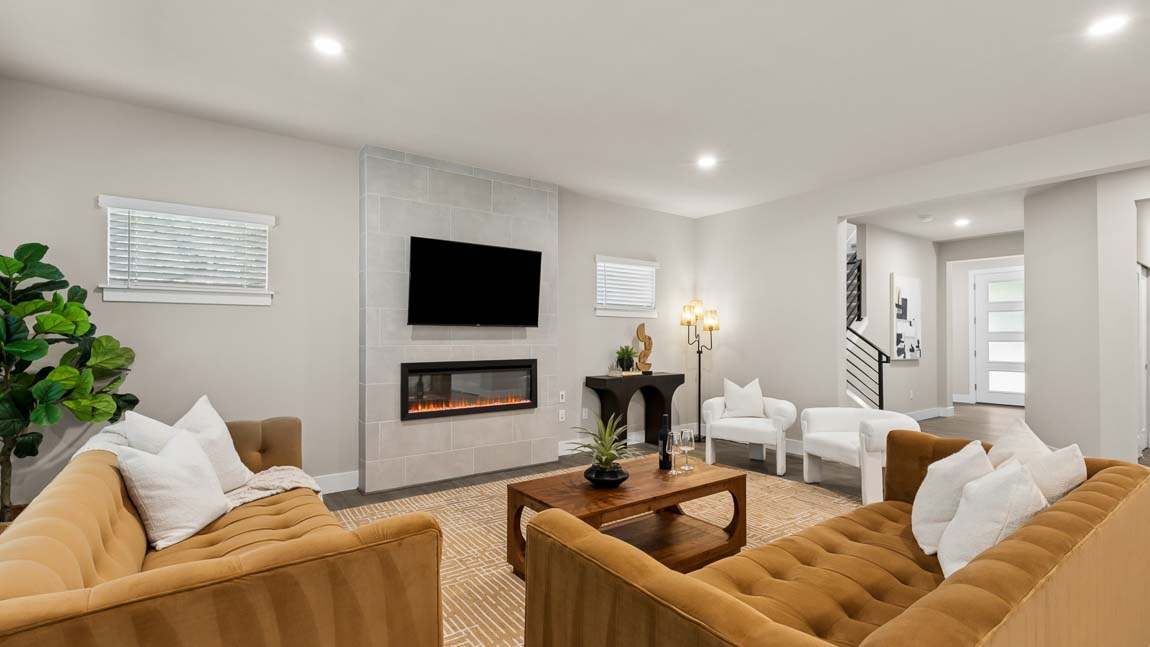 Open-concept living room with fireplace, wall-mounted television, neutral furnishings, and contemporary décor.