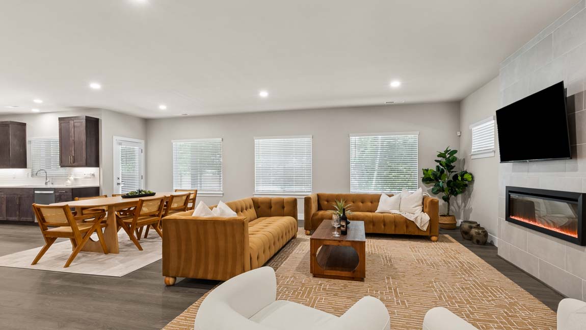 Open living and dining area with fireplace, large seating arrangement, and kitchen visible in the background.